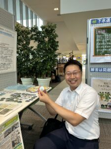 町田市下水道キャラクター雨かえるのバッチを手に